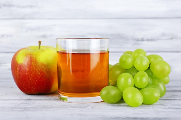 Zdjęcie szklanka soku ze świeżym winogronem i jabłkiem na szarym drewnianym stole