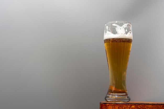 Zdjęcie szklanka świeżego i zimnego piwa na drewnianym stole na szarym tle