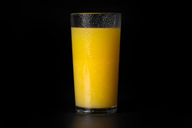 Szklanka świeżego soku pomarańczowego na czarnym tła zbliżeniu