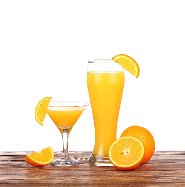 Szklanka świeżo wyciśniętego soku pomarańczowego z pokrojoną połówką pomarańczy na drewnianym stole