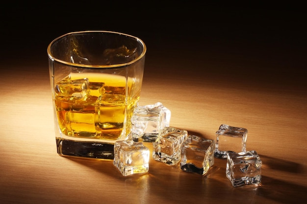 Szklanka szkockiej whisky i lodu na drewnianym stole