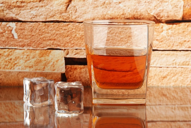 Szklanka whisky i lodu na tle ściany z cegły