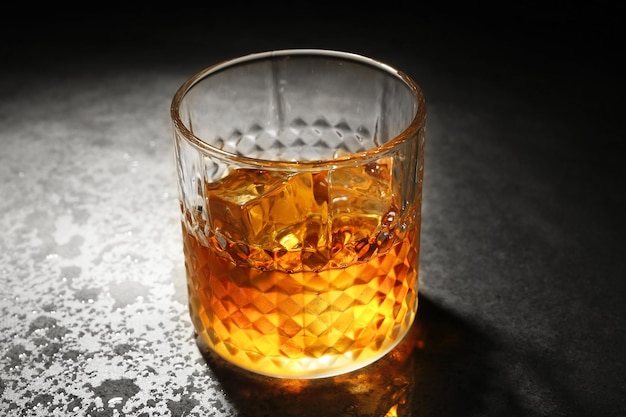 Szklanka whisky na szarym teksturowanym zbliżeniu stołu