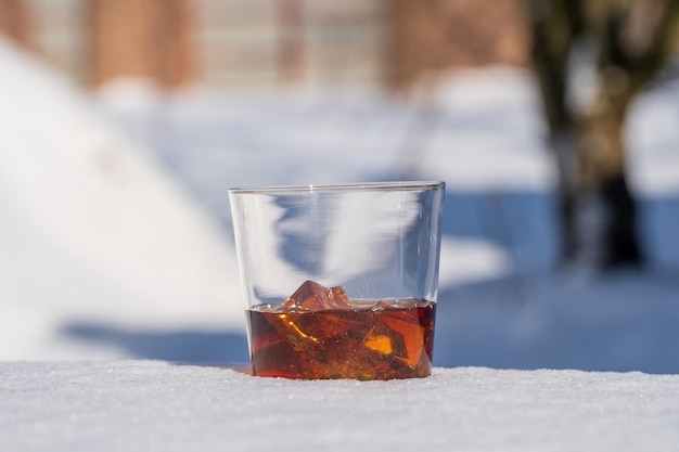 Szklanka whisky z lodem na łóżku ze śniegu i białego tła z bliska