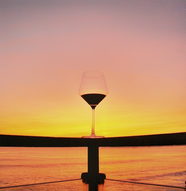 Zdjęcie szklanka wina przy zachodzie słońca nad morzem