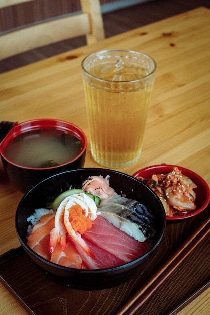 Szklanka wody i miska sushi z napojem na stole.