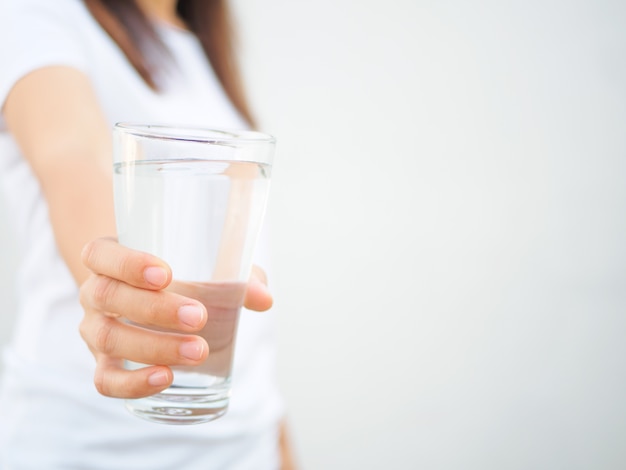 Szklanka wody mineralnej w rękach kobiety. Pojęcie zdrowego napoju.