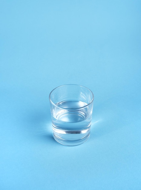 Szklanka wody na białym tle na niebieskim tle