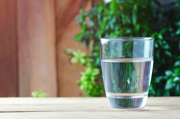 szklanka wody pitnej na drewnianym tle i zielonej przyrodzie