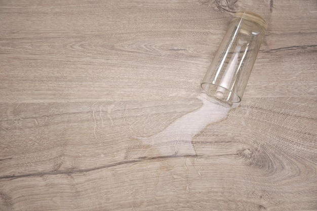 Szklanka wody spadła na wodę z laminatu rozlaną na podłogę