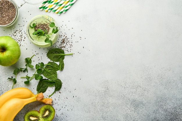 Szklanka Zdrowego Zielonego Smoothie I Składniki Na Smoothie, świeży Szpinak, Groszek Microgreens, Banan, Kiwi, Jabłko I Nasiona Chia Na Jasnoszarym Tle Betonu. Zdrowe Jedzenie Napojów. Widok Z Góry.