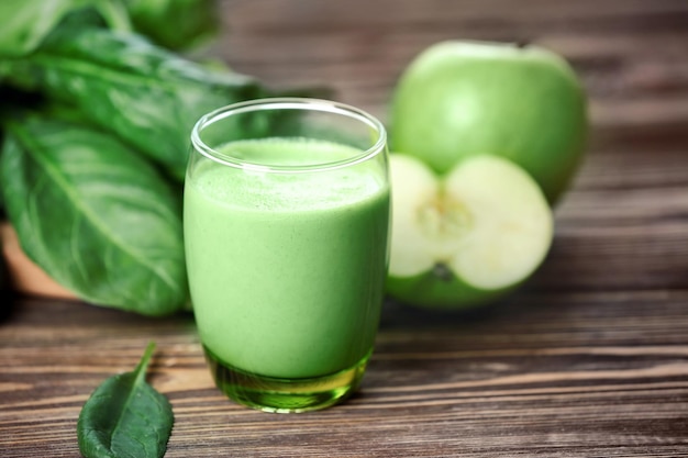 Szklanka zielonego zdrowego soku ze składnikami na drewnianym stole