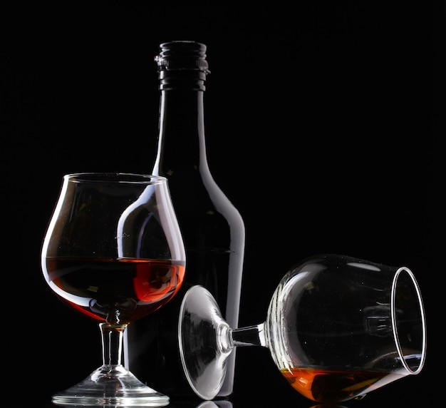 Szklanki brandy i butelki na czarnym tle