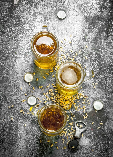 Zdjęcie szklanki piwa z otwieraczem do butelek i korkami na rustykalnym stole.