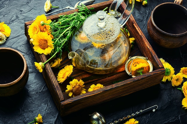 Szklany czajniczek z herbatą z kwiatów chryzantemy. Herbata kwiatowa. Medycyna ziołowa. Ziołolecznictwo i homeopatia. Herbata ziołowa.