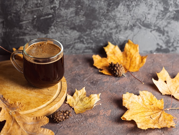 Szklany kubek kawy espresso z suchych liści jesienią