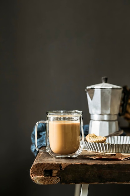 Zdjęcie szklany kubek z kawą stoi na stole obok patelni do naleśników jak zaparzyć kawę z mlekiem