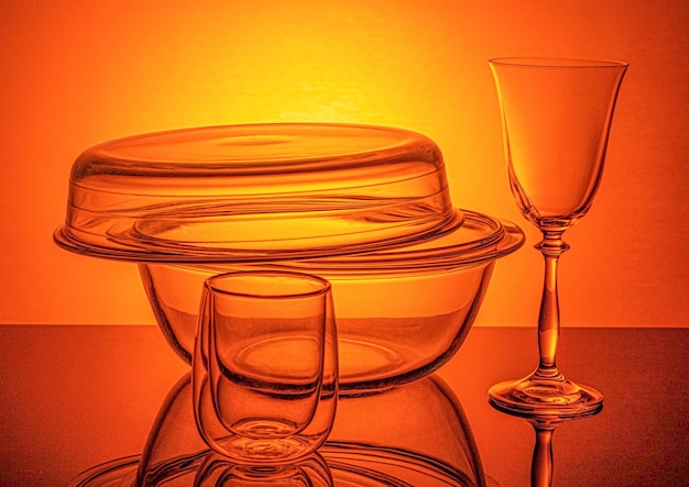 Szklany rondel żaroodporny i kieliszek do wina na pomarańczowym tle