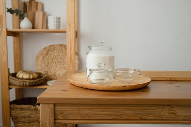 Szklany słoik mąki na drewnianym stole w kuchni