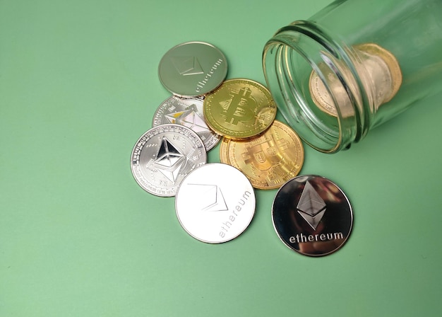 Szklany słoik ze srebrnym ethereum i złotą cyfrową kryptowalutą bitcoin na zielonym tle