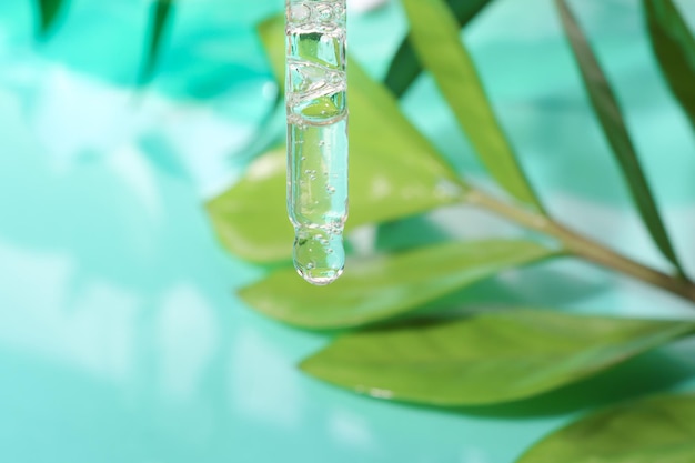Szklany zakraplacz z przezroczystym żelem na tle liści naturalne składniki przemysłu kosmetycznego