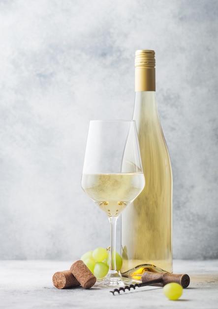 Zdjęcie szkło i butelkę białego wina z winogron i korkociąg na jasnym tle tabeli.