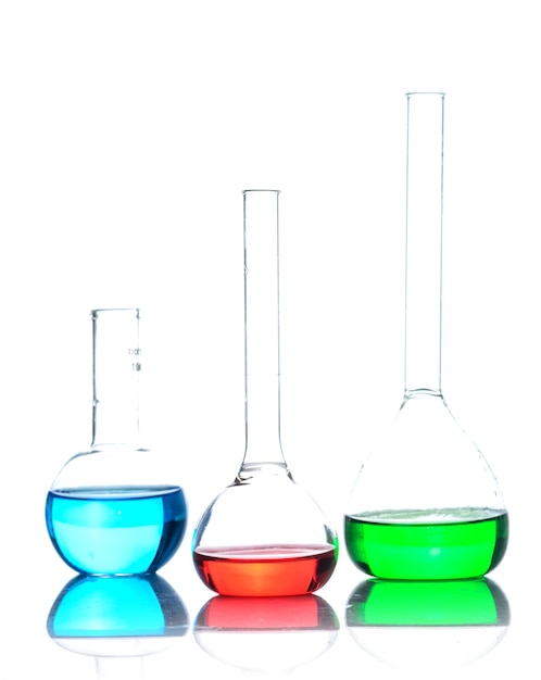 Zdjęcie szkło laboratoryjne z kolorowymi płynami nad odblaskowym stołem nad białym