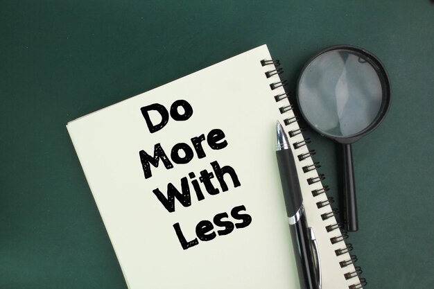 szkło powiększające, długopis i książka z napisem "Zrób więcej za mniej"