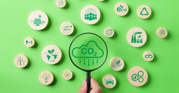 Szkło powiększające z koncepcją zmniejszenia emisji CO2 Ikony środowiskowe zmniejszają emisję CO2 Zmniejszenie śladu węglowego Odnawialna, czysta, zrównoważona energia Niska zawartość węgla Globalne ryzyko zmiany klimatu Net Zero ESG