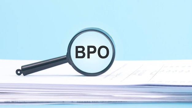 Szkło powiększające z napisem BPO Business Process Outsourcing na niebieskim tle