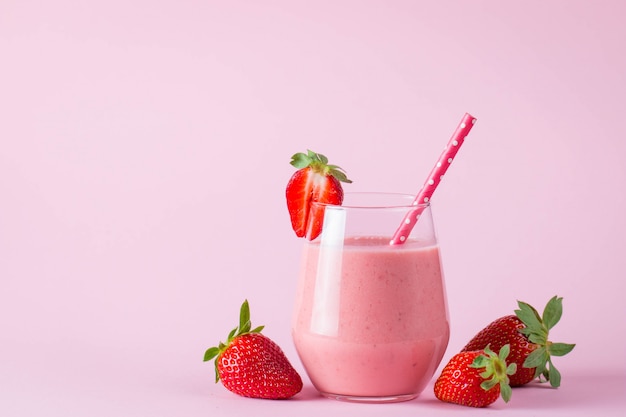 Szkło świeży truskawkowy milkshake, smoothie i świeże truskawki na różowym, białym i drewnianym tle ,. Koncepcja zdrowej żywności i napojów.