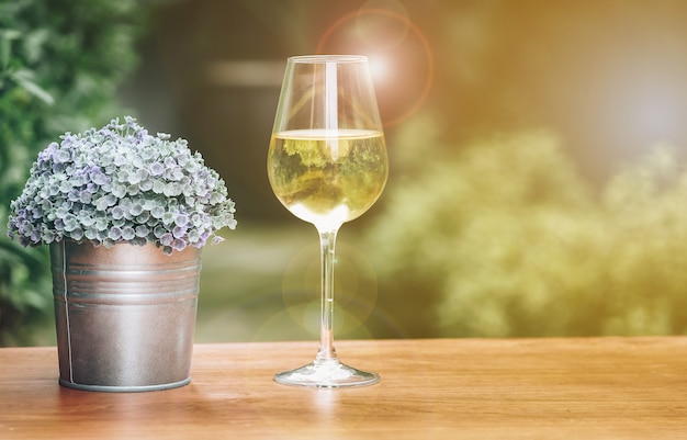 Zdjęcie szkło szampan i mała waza na drewnianym stole z ogródem jako tło zamazujący.