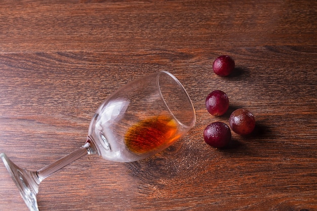 Szkło wino i czerwoni winogrona na drewnianym tle.