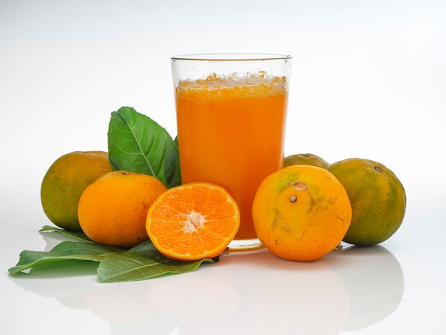 Szkło z sokiem pomarańczowym i owocami z zielonymi liśćmi