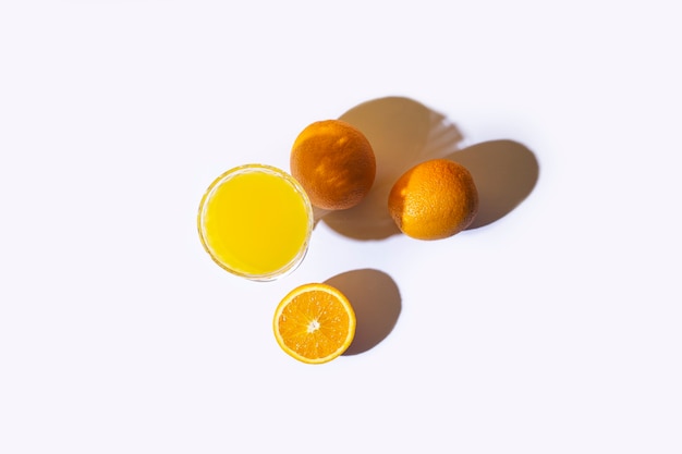 Szkło ze świeżym sokiem i pomarańczami na jasnym tle. Widok z góry, układ płaski