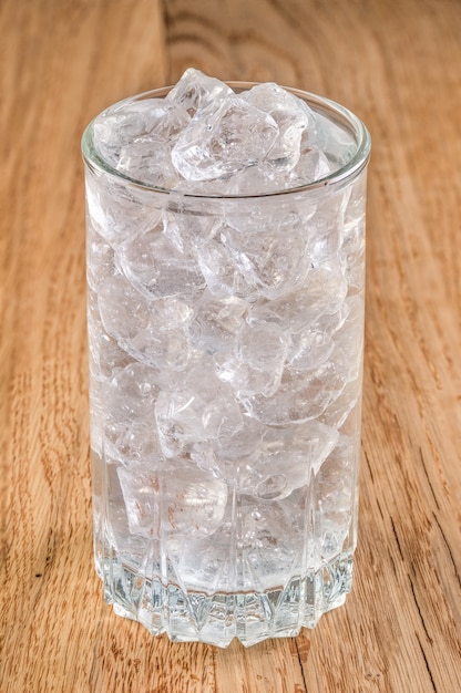 Szkło zimna woda z lodem na drewnianym stole
