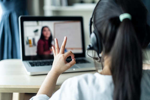 Szkoła domowa Azjatka uczy się wirtualnego Internetu online od nauczyciela szkoły przez zdalne spotkanie z powodu pandemii COVID Kobieta uczy matematyki za pomocą słuchawek i tablicy.