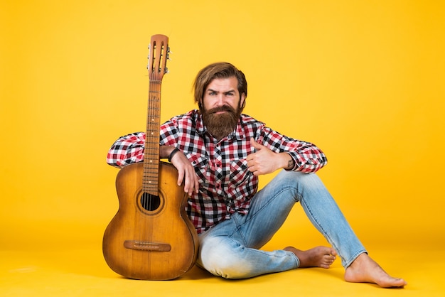 Szkoła muzyczna. styl muzyki country. człowiek ubrany w kraciaste koszule i przytrzymaj gitarę. grać na strunowym instrumencie muzycznym. profesjonalny muzyk kaukaski. gitarzysta. hipster człowiek grający na gitarze akustycznej.