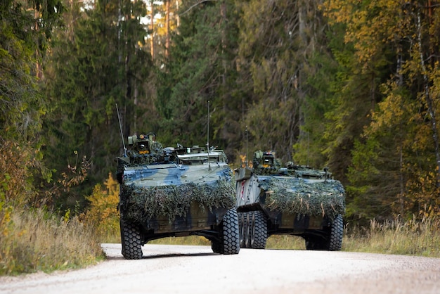 Szkolenie wojskowe na polu bitwy z pojazdami opancerzonymi jeżdżącymi po leśnej drodze Koncepcja wojny armii