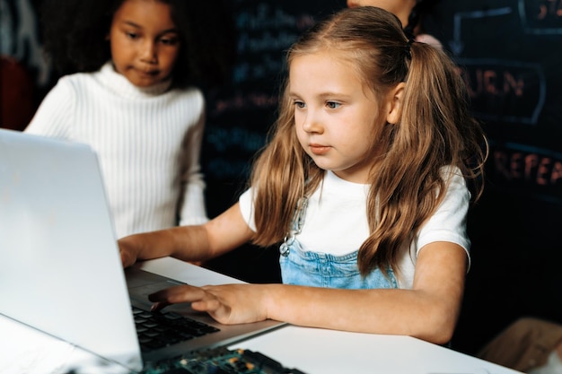 Zdjęcie szkolka w białym bibie uczy się technologii robotyki za pomocą laptopa