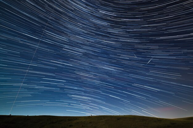 Szlak gwiazd na nocnym niebie z jasnymi meteorami i światłami samolotów.