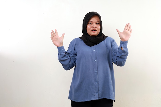 Szokowana azjatycka muzułmańska kobieta stojąca podnosząc ręce
