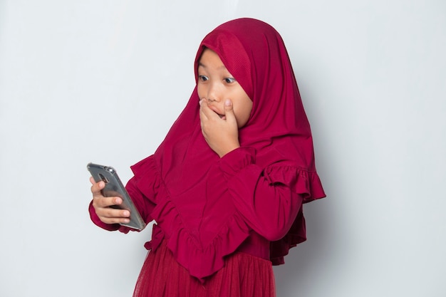 Szoku Muzułmańskiej Azjatykciej Małej Dziewczynki Używającej Smartfona Na Białym Tle