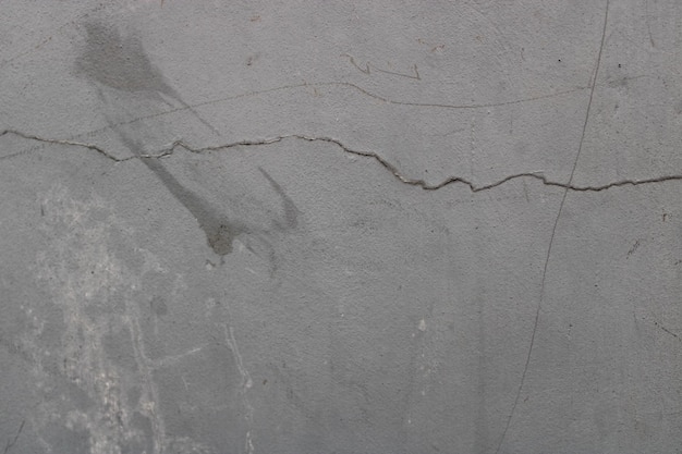 Szorstka tekstura starej szarej pękniętej ściany na ścianie
