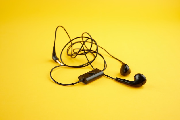 Zdjęcie szot słuchawek na jasnożółtym tle. ilustracja zamieszania. minimalna koncepcja