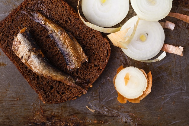 Zdjęcie szproty w puszce w puszce z chlebem żytnim. na rustykalnej powierzchni