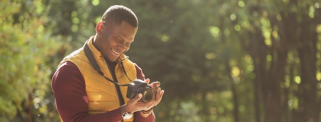 Sztandarowy afroamerykanin fotograf robi zdjęcie aparatem fotograficznym na miejskim zielonym parku kopia sp