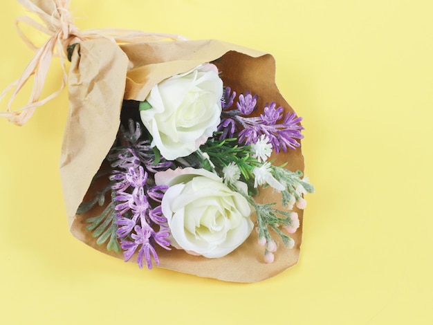 Sztuczny bukiet wiosennych kwiatów w papierze rzemieślniczym na żółtym tle