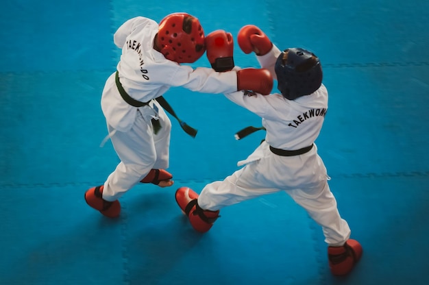 Sztuki walki Taekwondo Dzieci w tradycyjnych kimano, kaskach i rękawiczkach Sportowy pojedynek Dla nastrojowego efektu szumu filmu Tekst Taekwondo to nazwa sztuki walki