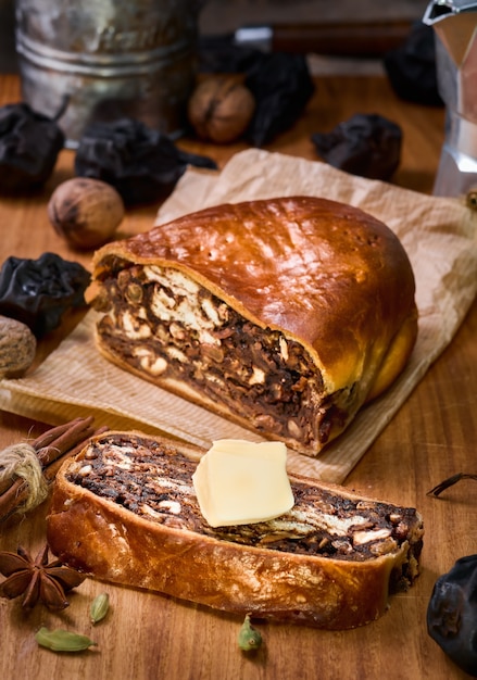 Szwajcarski chleb gruszkowy lub Birnbrot to lokalne ciasto nadziewane suszonymi gruszkami i owocami. Selektywne skupienie. Pokrojone w ćwiartki muffinki, obok masło. Fotografia pionowa